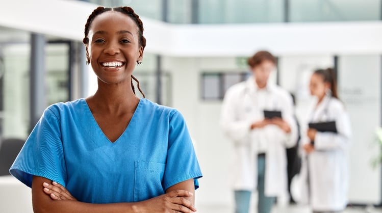 smiling black female in O-R scrubs with two females wearing lab coats in background